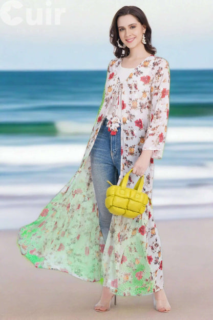 Woman at beach wearing floral cover-up with yellow woven handbag, standing confidently and smiling.