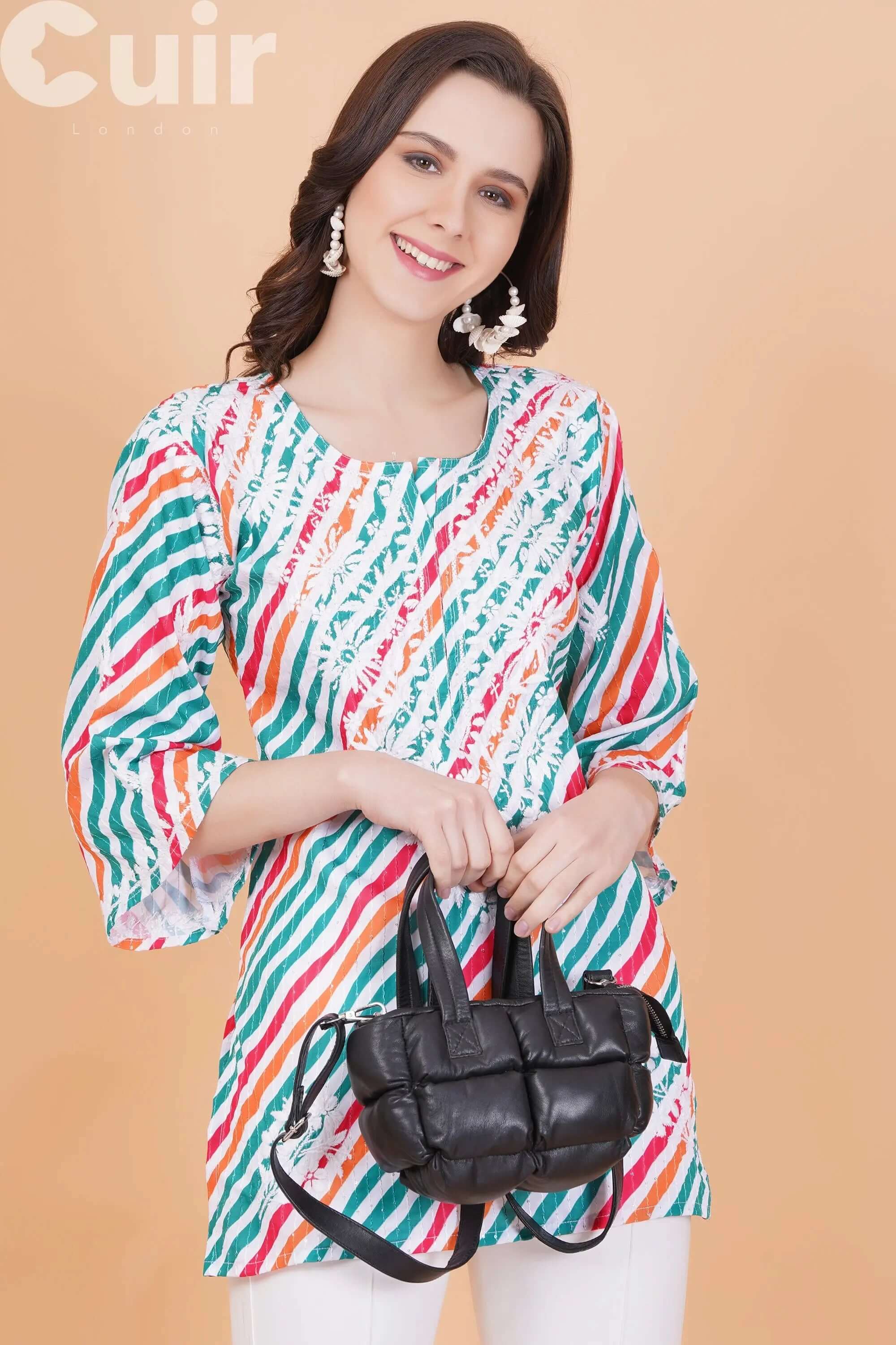 Woman in colorful striped top holding a black genuine leather crossbody bag with adjustable strap.