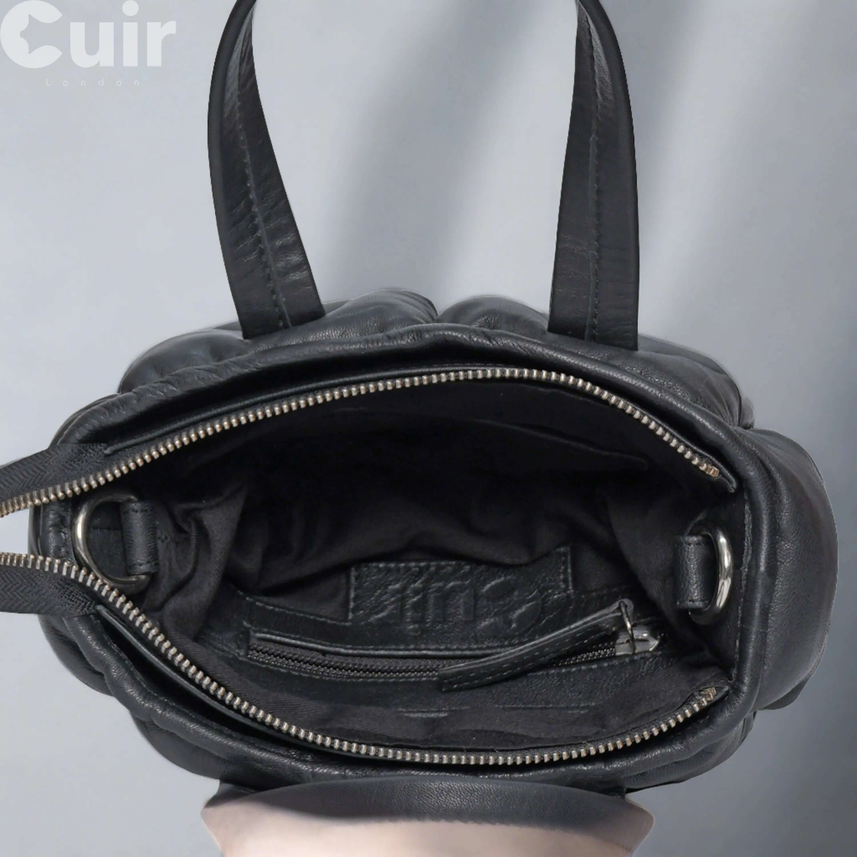 Open view of women's black genuine leather crossbody bag showing interior compartments and zipper detail.